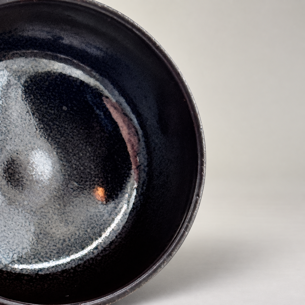 Kuro-yū Chawan – Nahaufnahme der Innenglasur auf neutralem Hintergrund