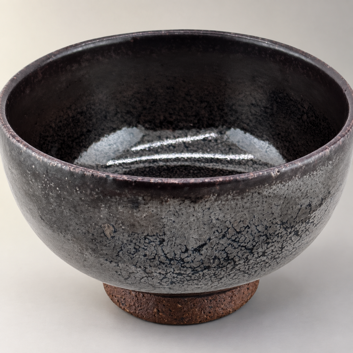 Kuro-yū Chawan – Schrägansicht mit Innenglasur auf neutralem Hintergrund
